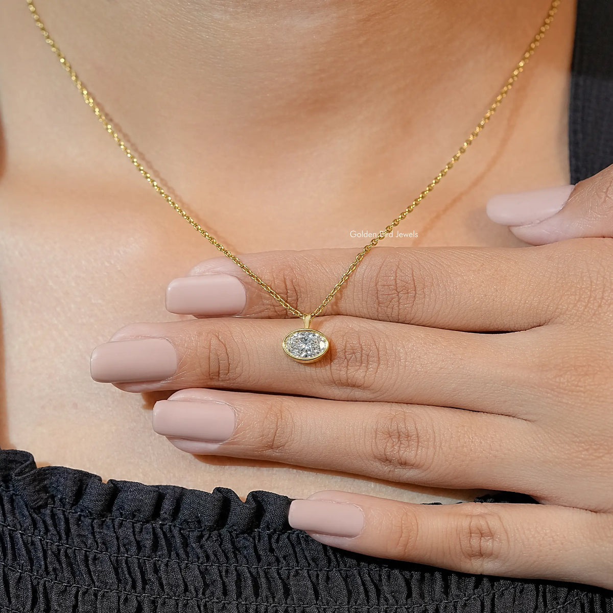Gold-tone oval lab diamond solitaire pendant necklace with hands resting on it