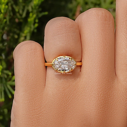 Oval moissanite solitaire ring close-up with gold-tone band and faceted center stone.