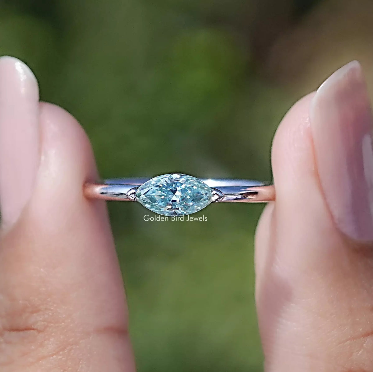 Front view of East West Marquise Cut Moissanite Solitaire Ring in two fingers 