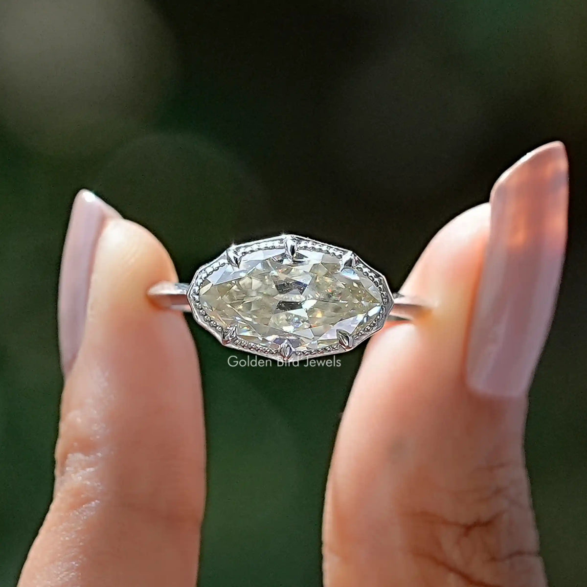 Two fingers holding the East West Old Mine Moval Cut Moissanite Ring