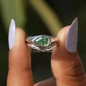 Two fingers holding the Green Pear Cut Moissanite Solitaire Ring Set
