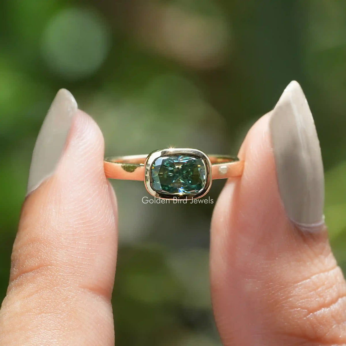 Two fingers holding the Elongated Cushion Moissanite Solitaire Ring