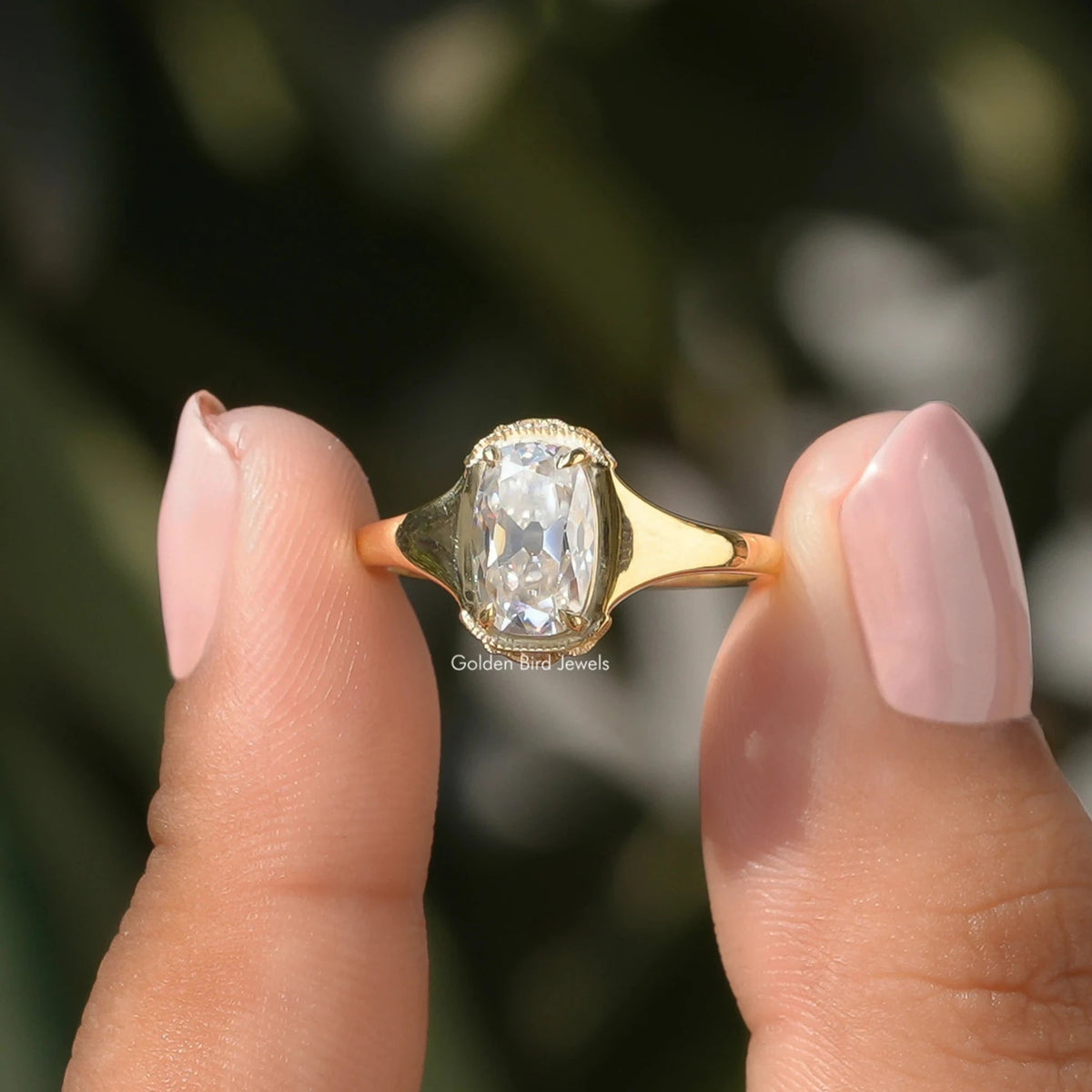 Two fingers holding the Elongated Old Mine Cushion Cut Moissanite Ring
