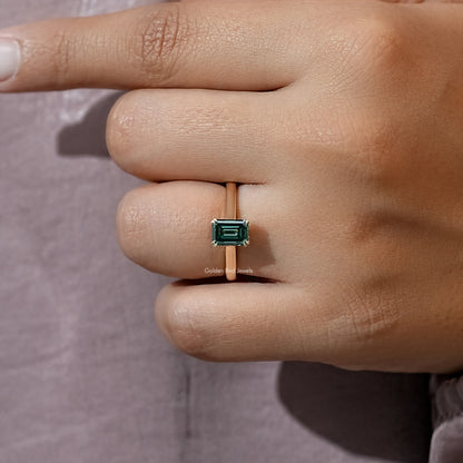 Emerald-cut moissanite engagement ring close-up with dark green rectangular stone