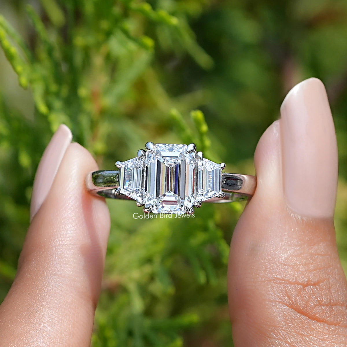 Front View of Emerald Cut Lab Diamond Three Stone Ring In two Fingers