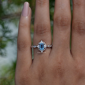 Detailed View of A Blue Topaz Emerald Cut Halo Ring In white Gold