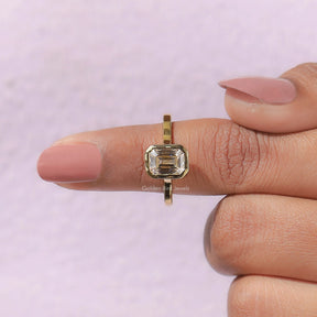 In finger front View of Solitaire Emerald Cut Moissanite Ring In Yellow Gold