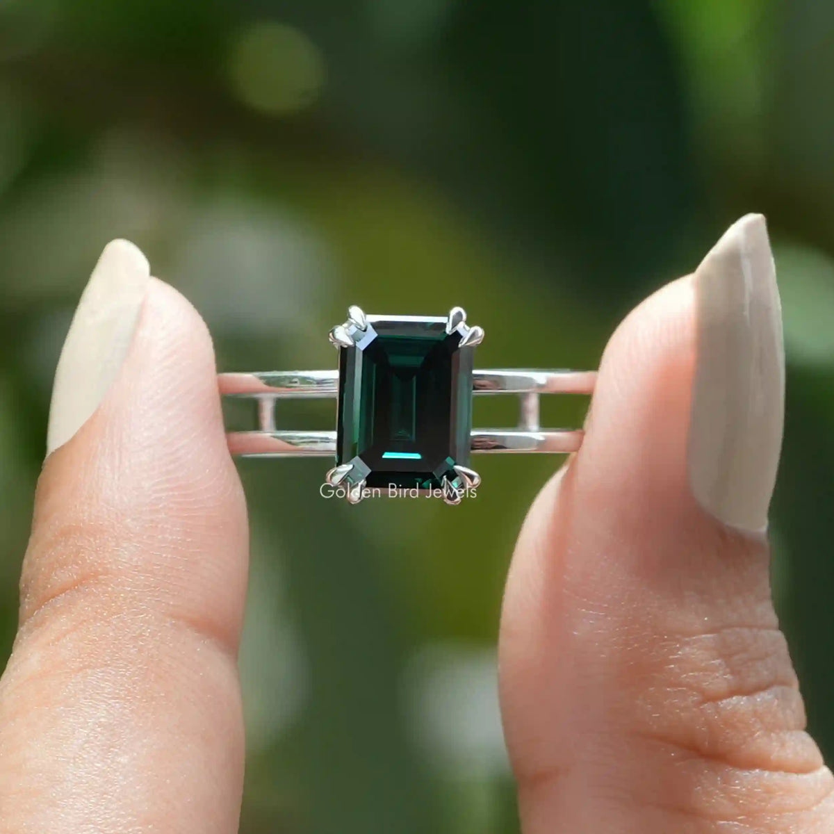 Two fingers holding the Emerald Cut Moissanite Solitaire Engagement Ring