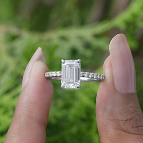 Two fingers holding the Emerald Cut Solitaire Diamond Ring