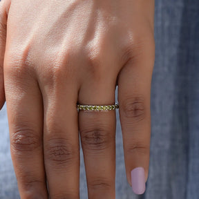 In finger front view of August Birthstone Peridot Green Round Eternity Band in unique shape