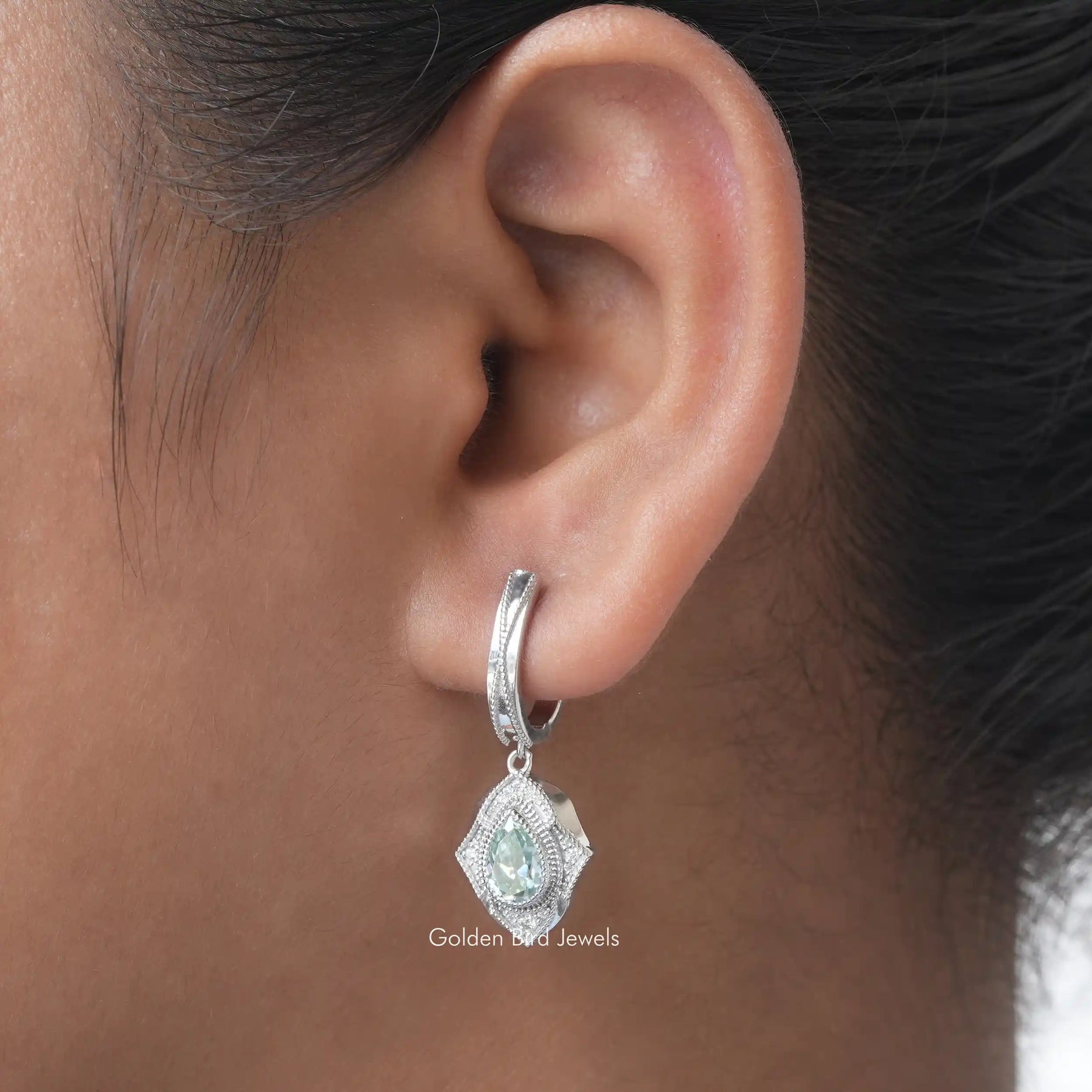 [In ear front view of blue pear and round cut moissanite earrings]-[Golden Bird Jewels]