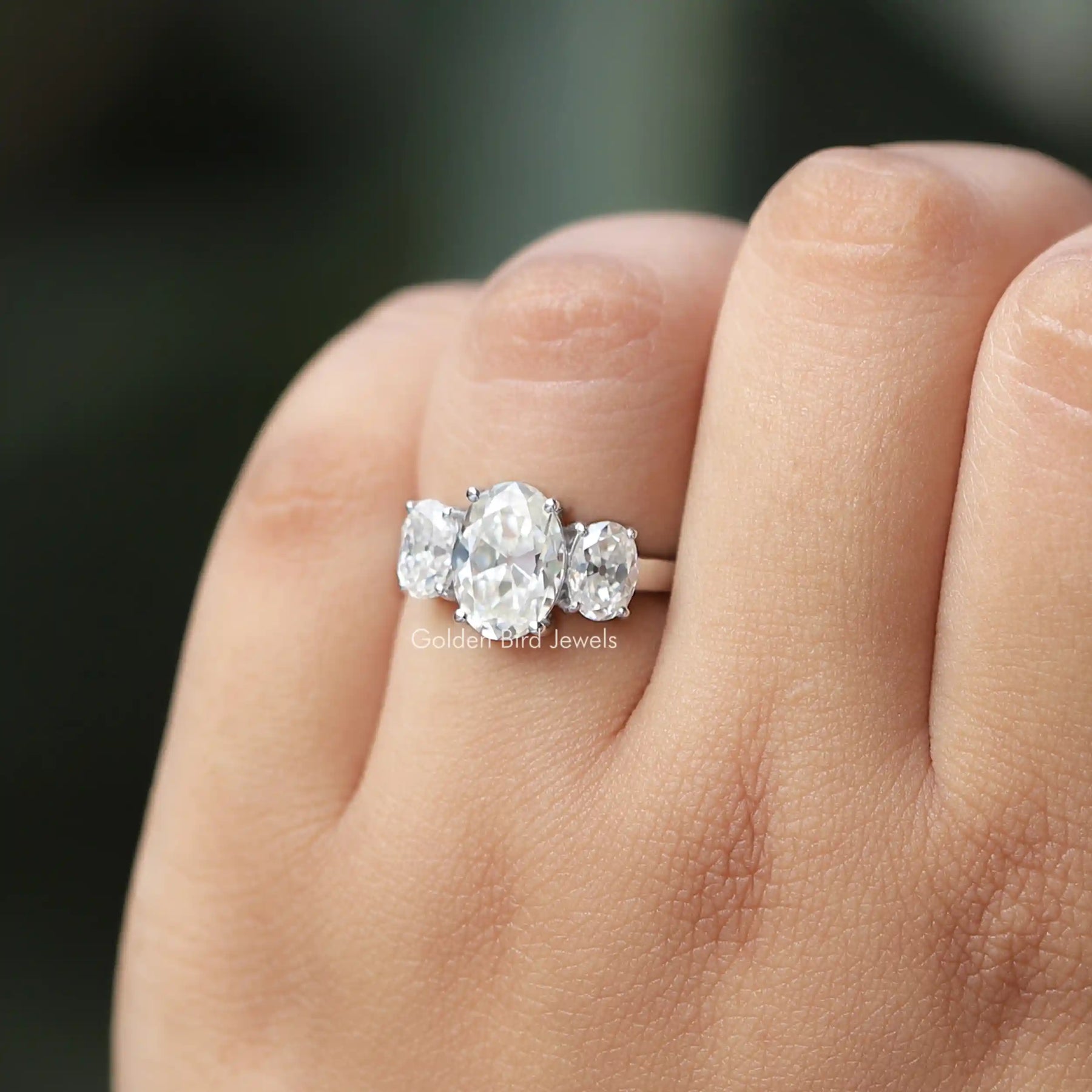 [In hand front view of oval cut moissanite engagement ring]-[Golden Bird Jewels]