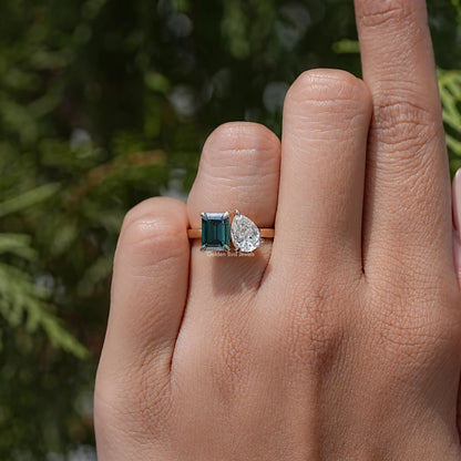 Two-stone ring on finger, emerald-cut green stone with round white side stone