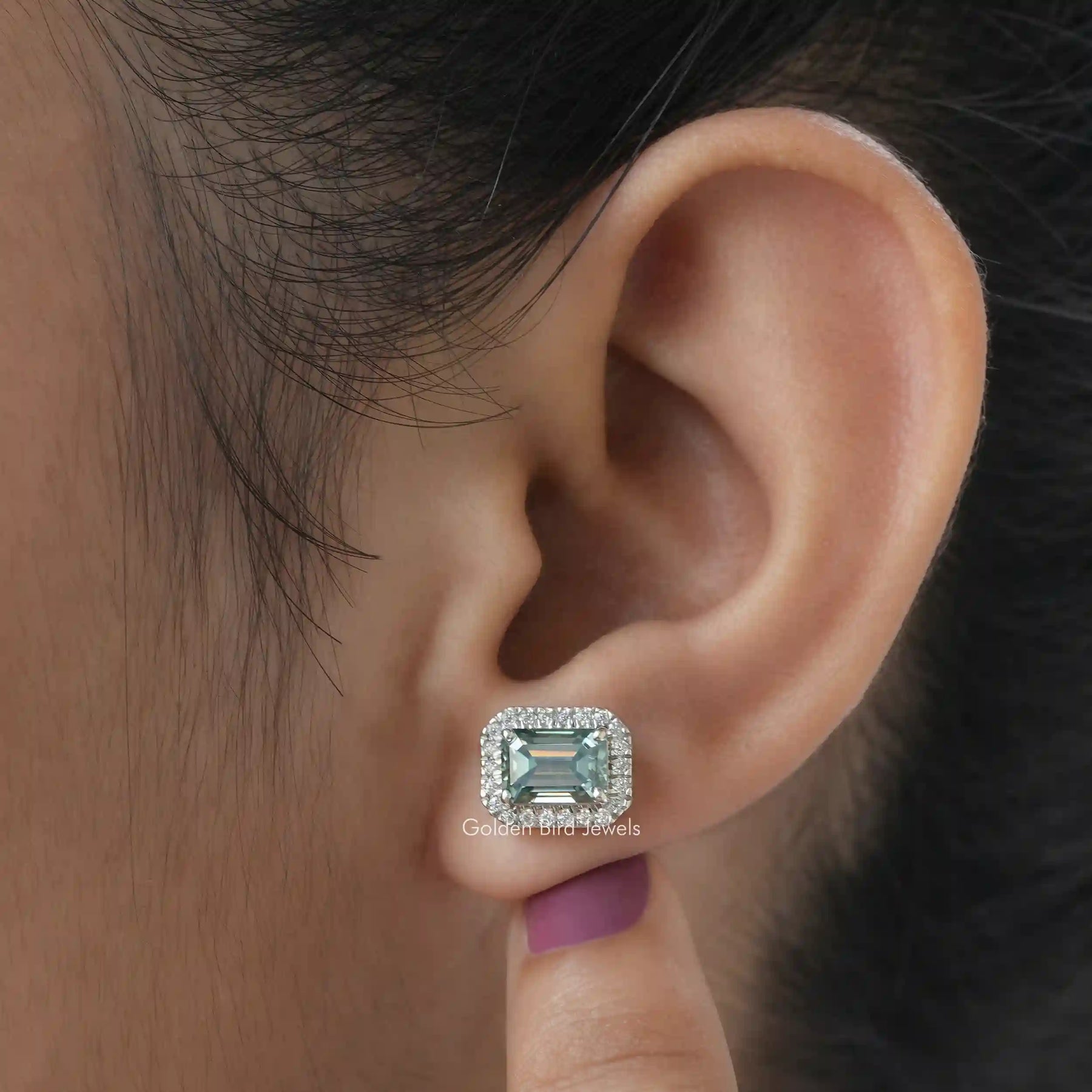 [In ear front view of green emerald cut stud earrings made of white gold]-[Golden Bird Jewels]