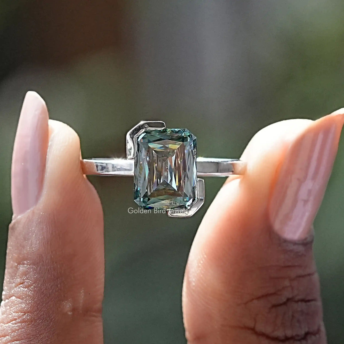 Two fingers holding the Half Bezel Set Criss Cut Moissanite Solitaire Ring