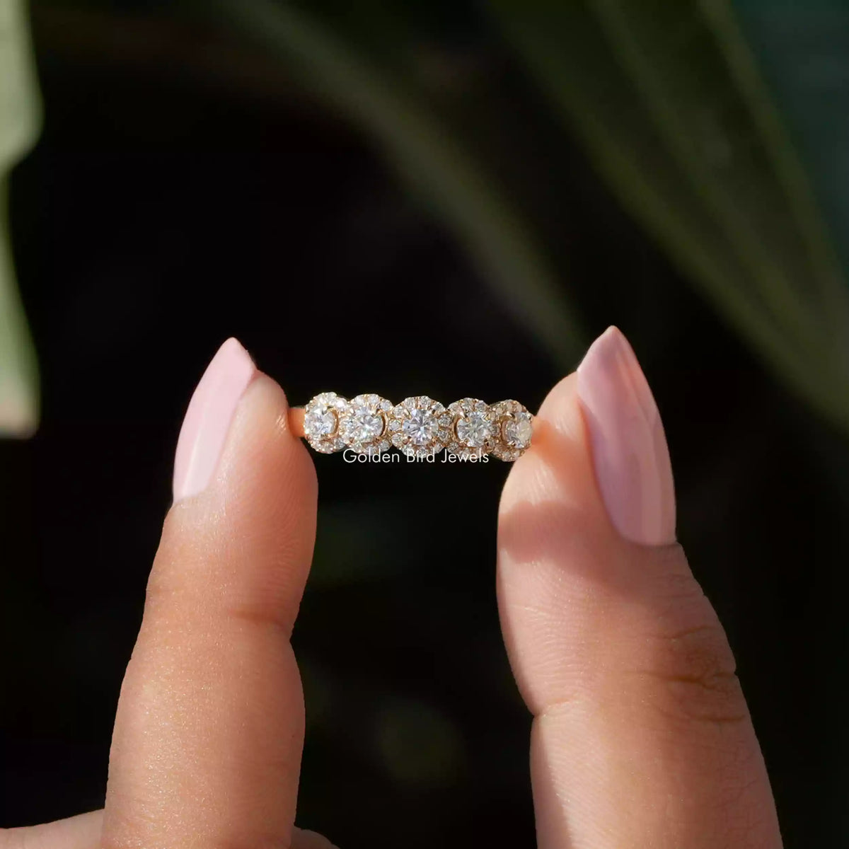 Two fingers holding the Moissanite Round Cut Wedding Band