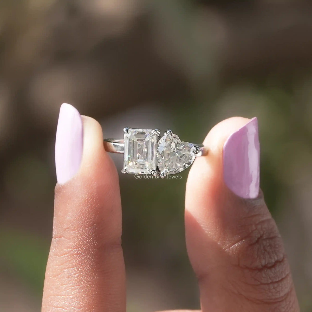 Emerald Cut Moissanite ring holding on two fingers 
