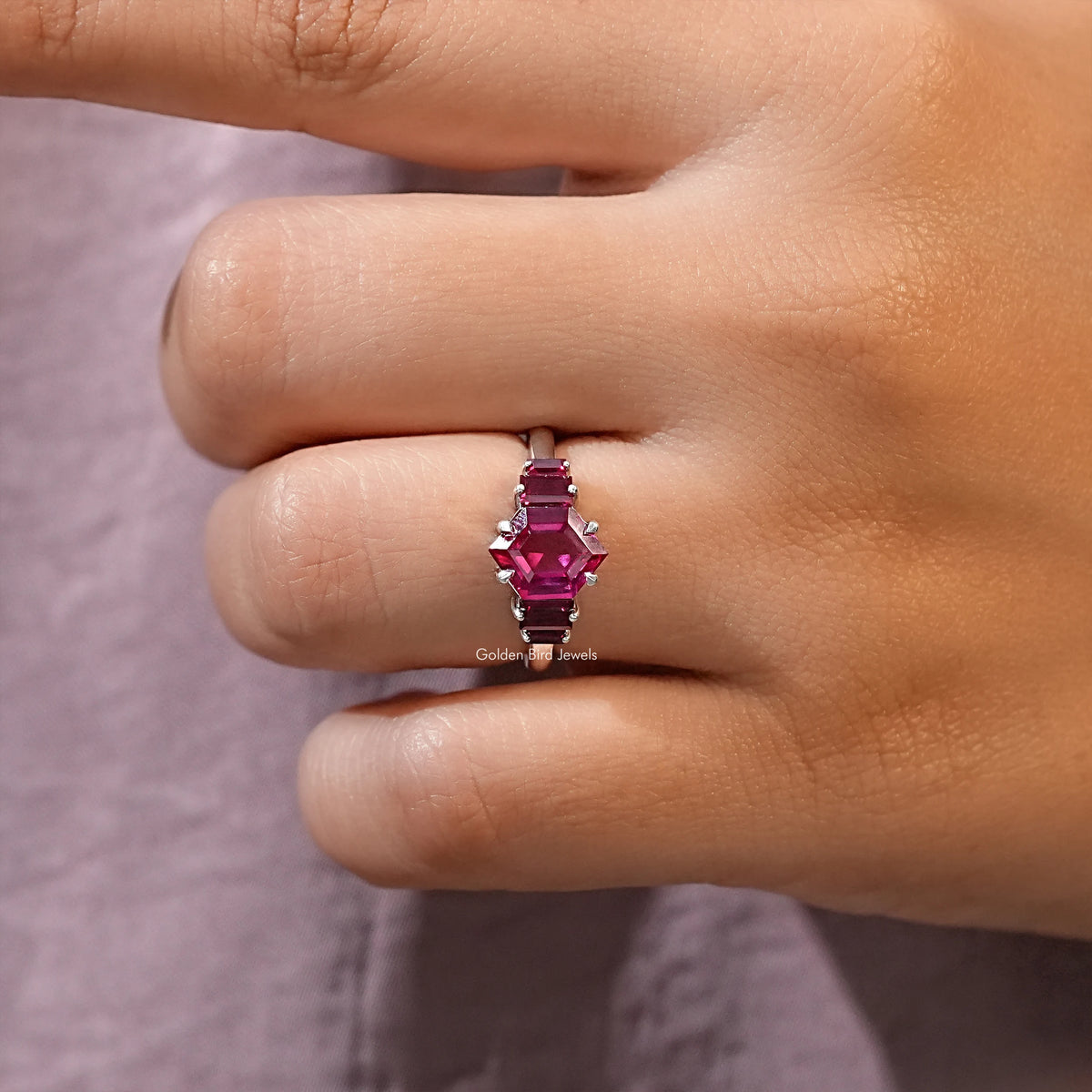 Ruby red hexagon-cut center gemstone with four side stones on slim silver ring band