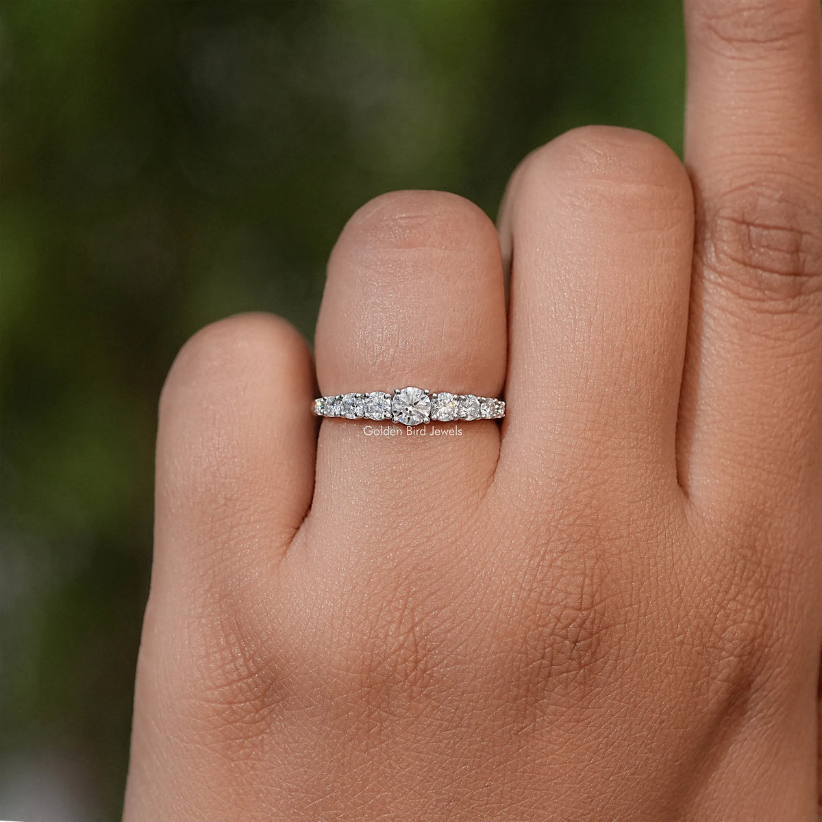 Moissanite engagement ring with slim band of round stones shown on finger