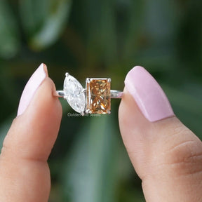 Two fingers holding the Champagne Radiant Cut Toi Et Moi Ring