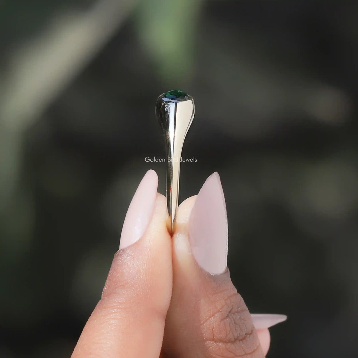 Side View of Bezel Set Marquise Cut Solitaire Engagement Ring In two fingers