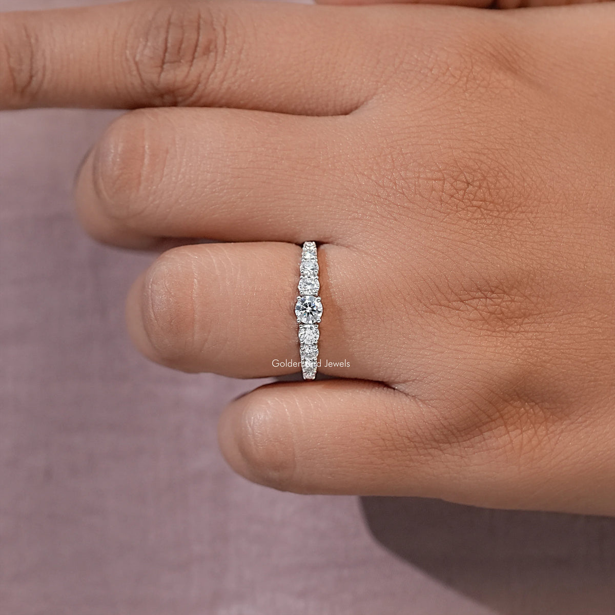 Silver-toned moissanite engagement ring with small round stones on a half-eternity band