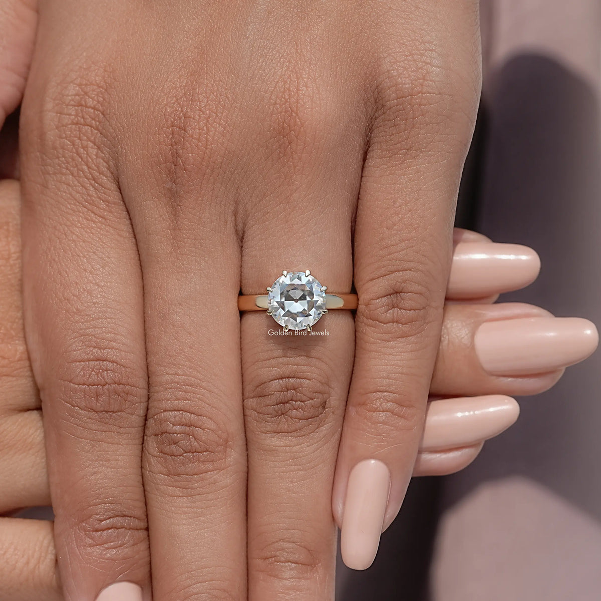 Round moissanite solitaire ring close-up on fingers, prong-set center stone and band