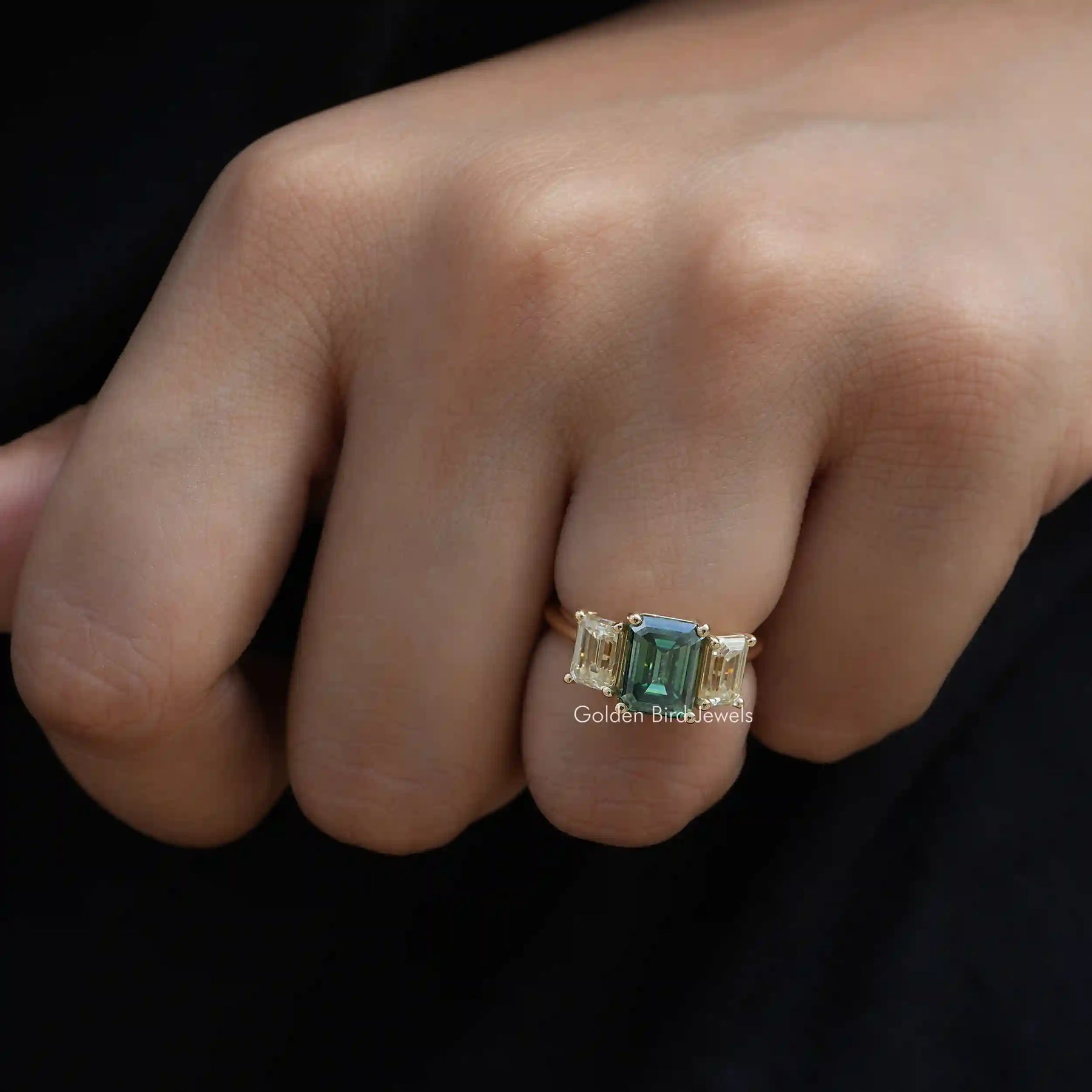 [In finger front view of 3 stone emerald cut moissanite ring crafted with 14k yellow gold]-[Golden Bird Jewels]