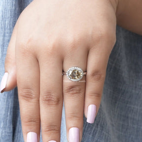 [In finger front view of oval cut halo style moissanite ring]-[Golden Bird Jewels]