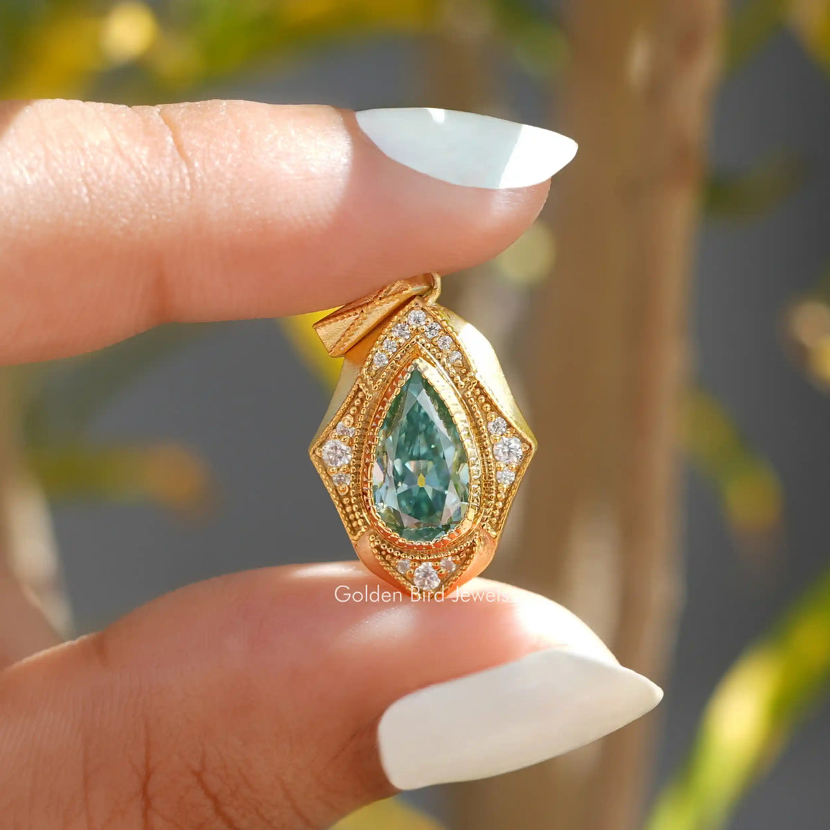 In two finger front view of blue pear cut moissanite pendant