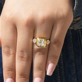[In hand front view of yellow gold three stone cushion cut moissanite ring]-[Golden Bird Jewels]