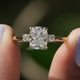 Cushion Cut Diamond Three Stone Wedding Ring held between fingers 