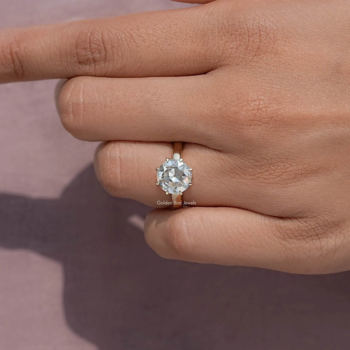 Round moissanite solitaire ring close-up with prong-set stone on hand