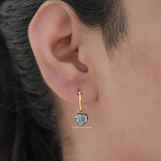 Gold-tone dangle drop earring with heart-cut moissanite stone on ear