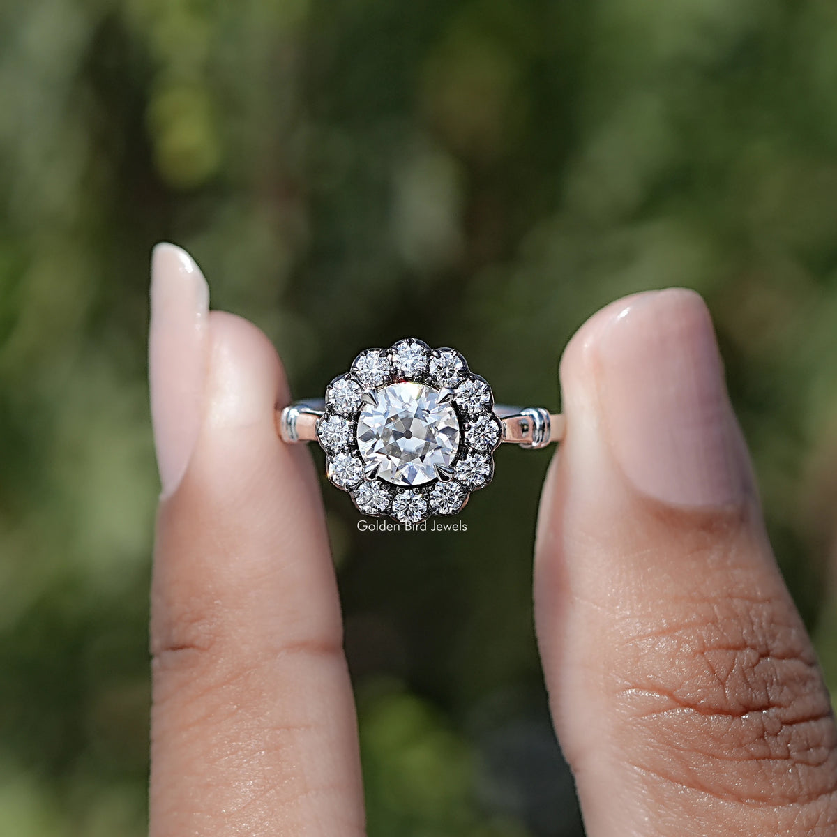 Front view of Old European Cut Round Moissanite Halo Ring in two fingers 