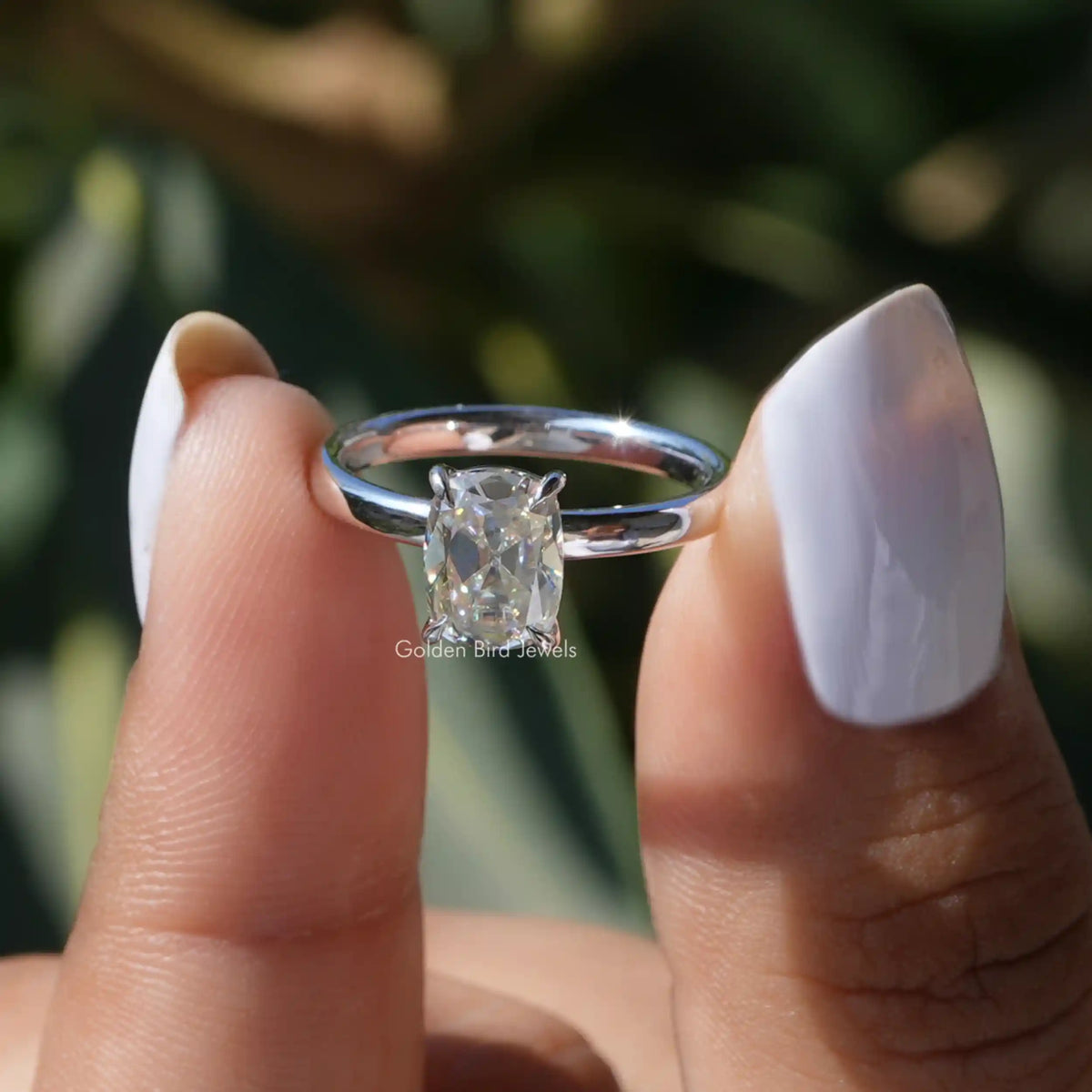 Two fingers holding the Old Mine Cushion Cut Moissanite Solitaire Ring