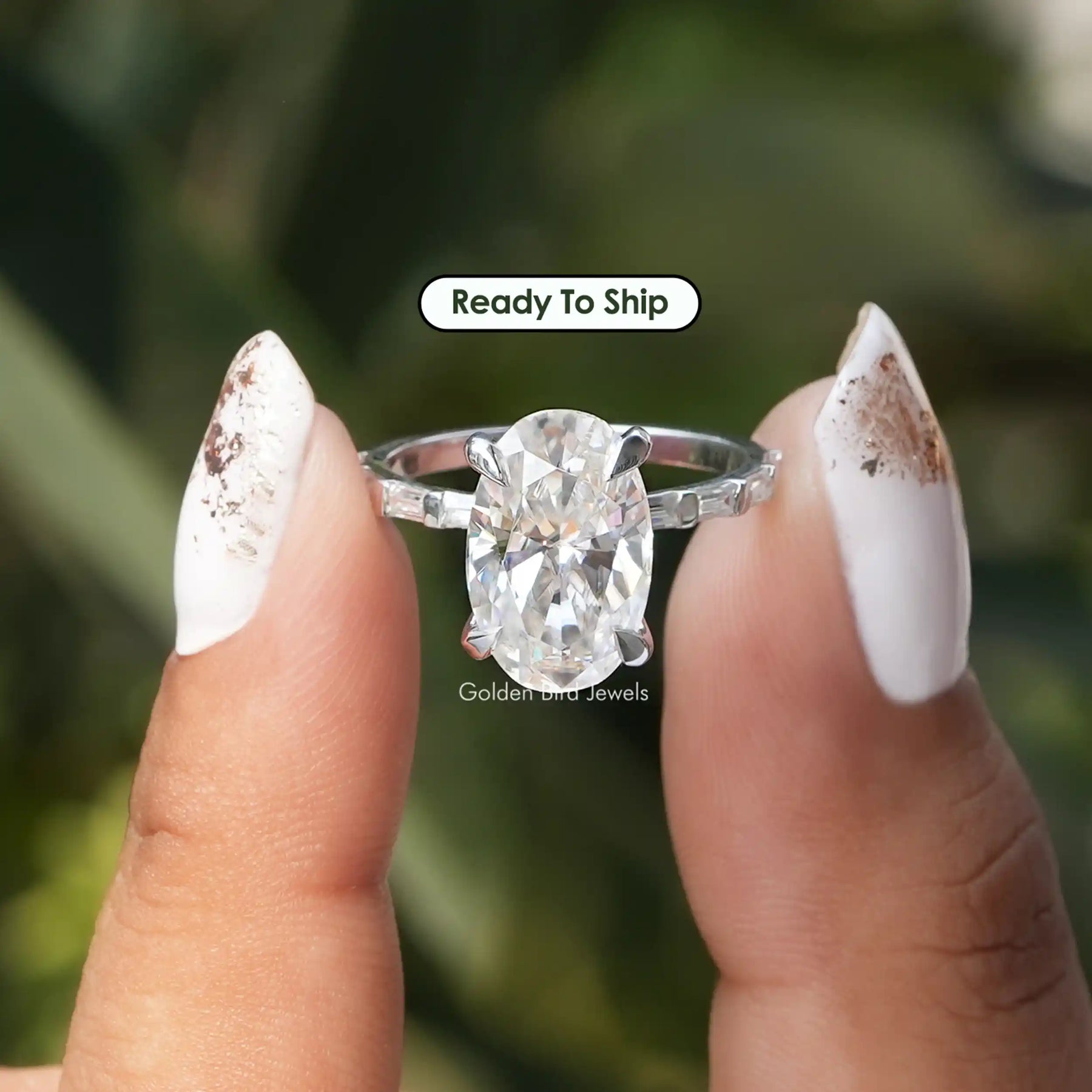 [In two finger front view of oval cut moissanite ring]-[Golden Bird Jewels]