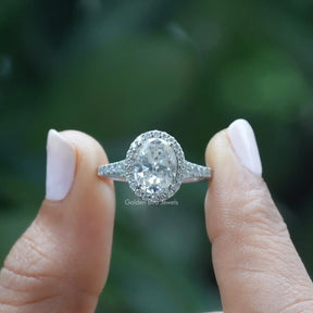 [In two finger front view of oval cut halo engagement ring]-[Golden Bird Jewels]