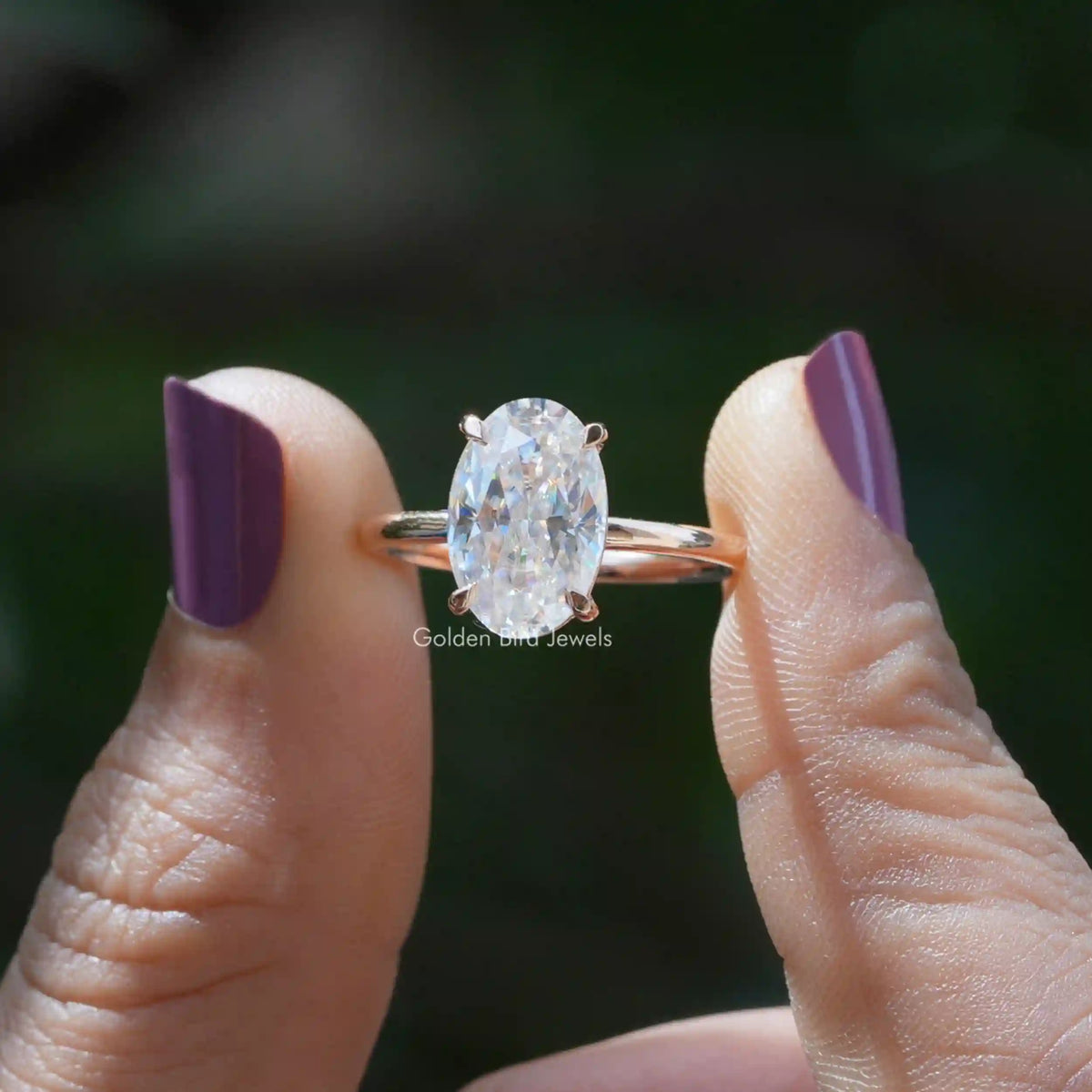 Two fingers holding the Moissanite Oval Cut Solitaire Engagement Ring