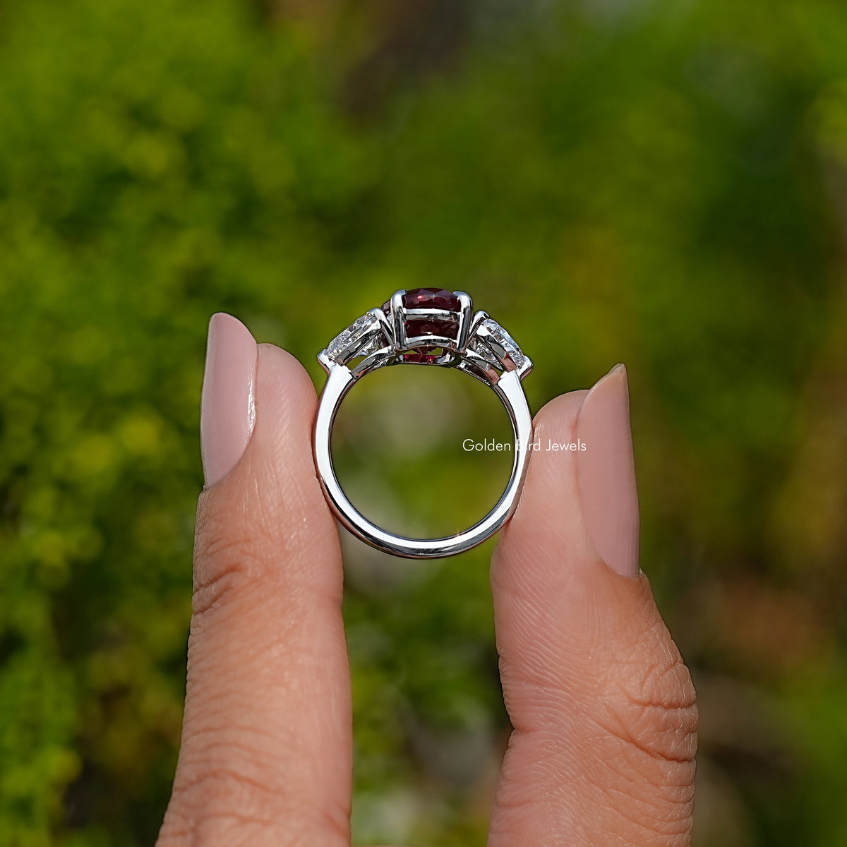 Three-stone ruby ring with oval center, viewed from above, bright metal band