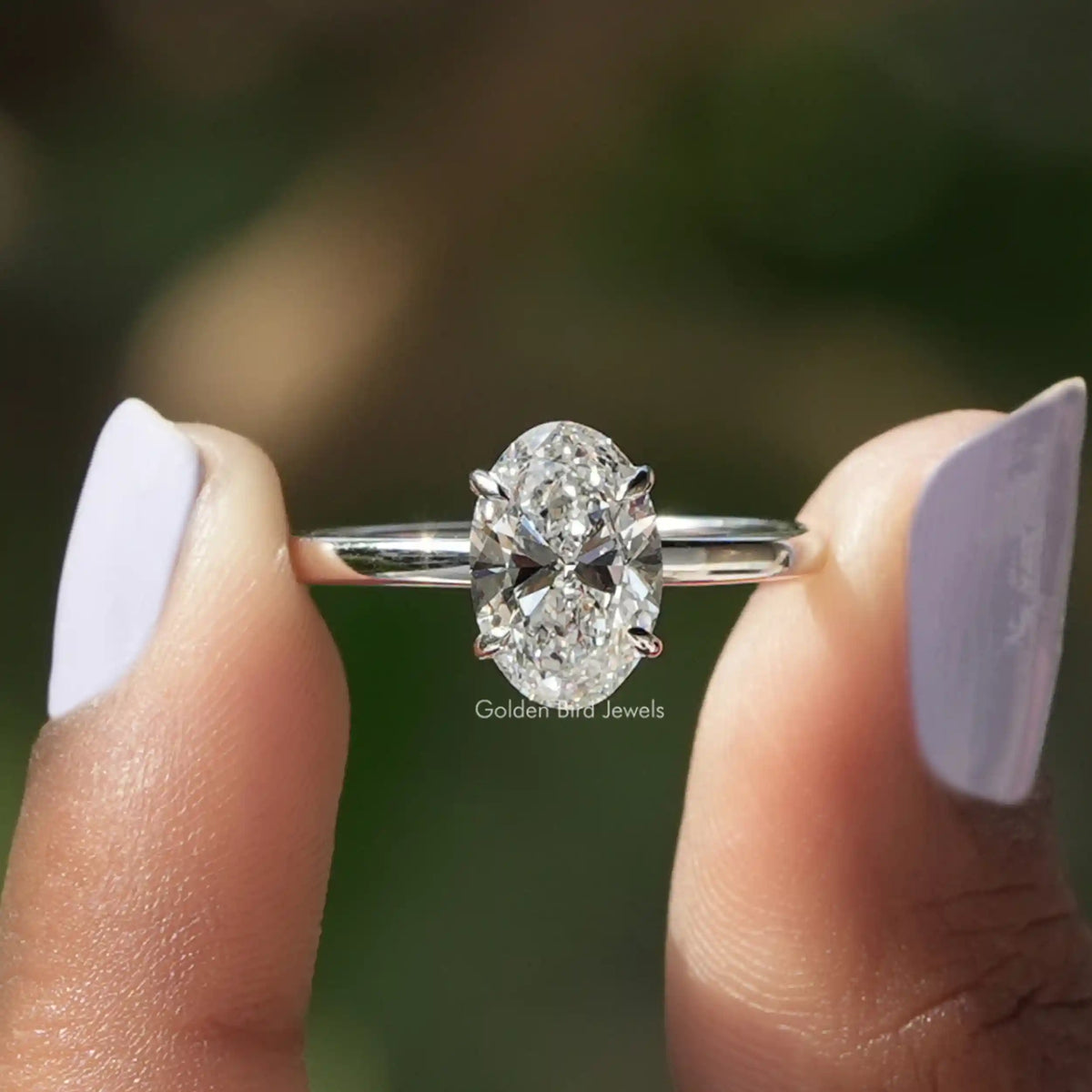 Two fingers holding the Oval Cut Lab Diamond Solitaire Engagement Ring