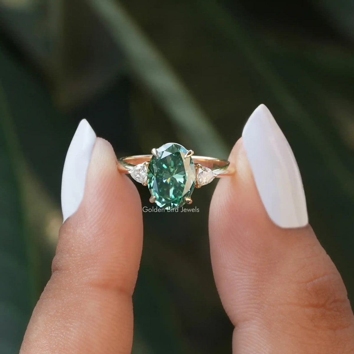 Two fingers holding the Oval Cut 3 Stone Moissanite Engagement Ring