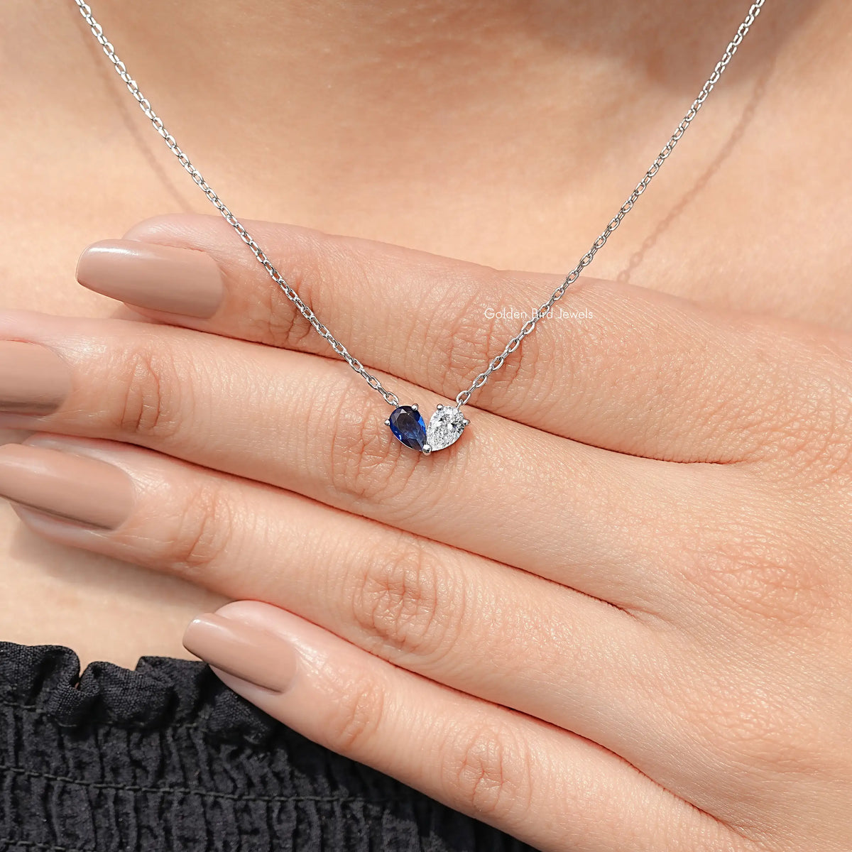 Sterling silver pendant necklace in hand, blue pear stone with clear companion