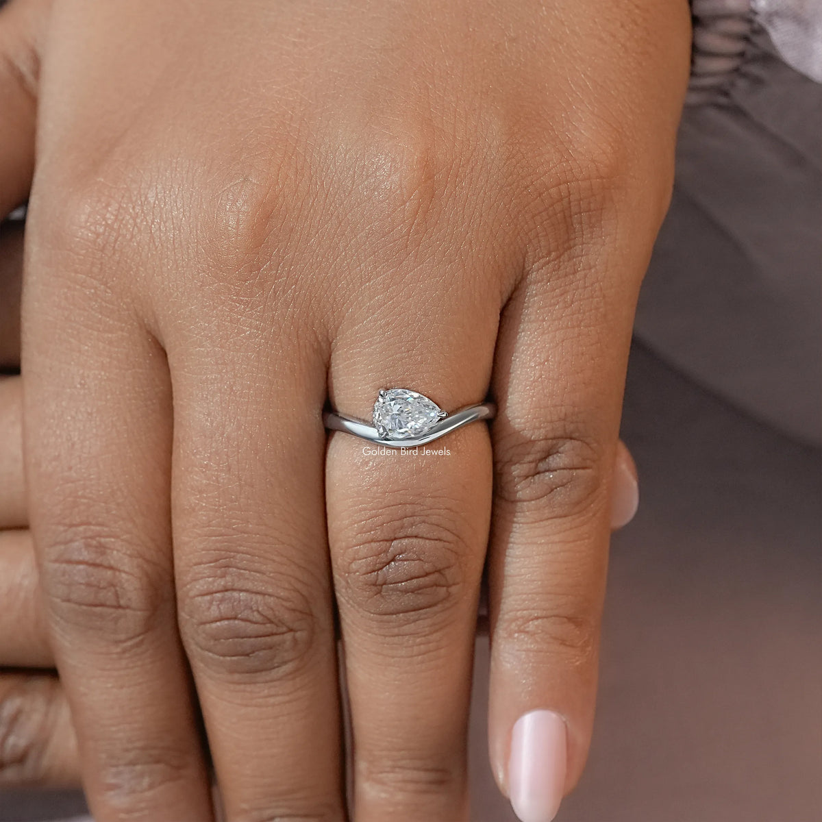 Pear-cut moissanite solitaire engagement ring centered on hand
