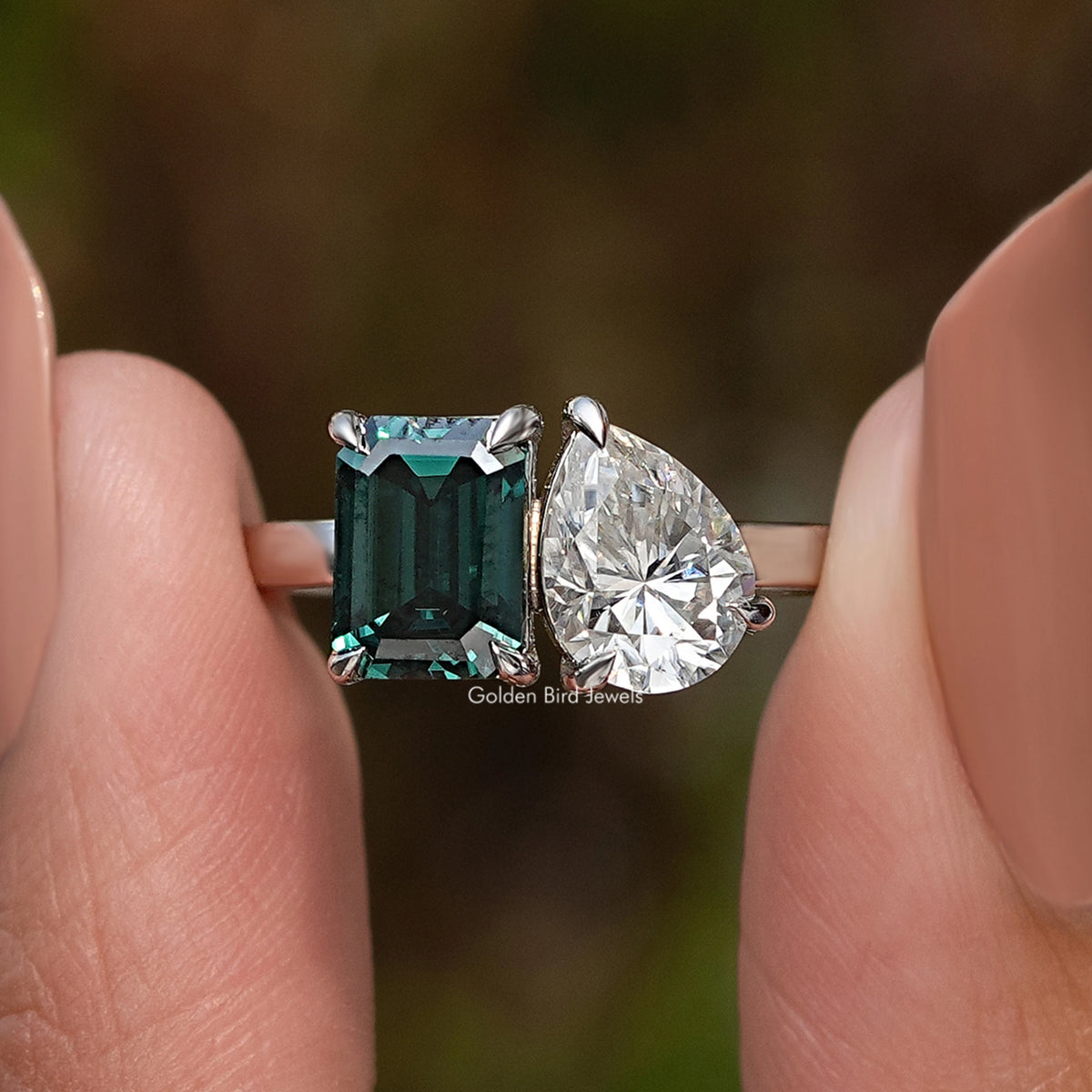 Toi Moi moissanite ring with a green emerald-cut stone and a contrasting white pear-cut stone