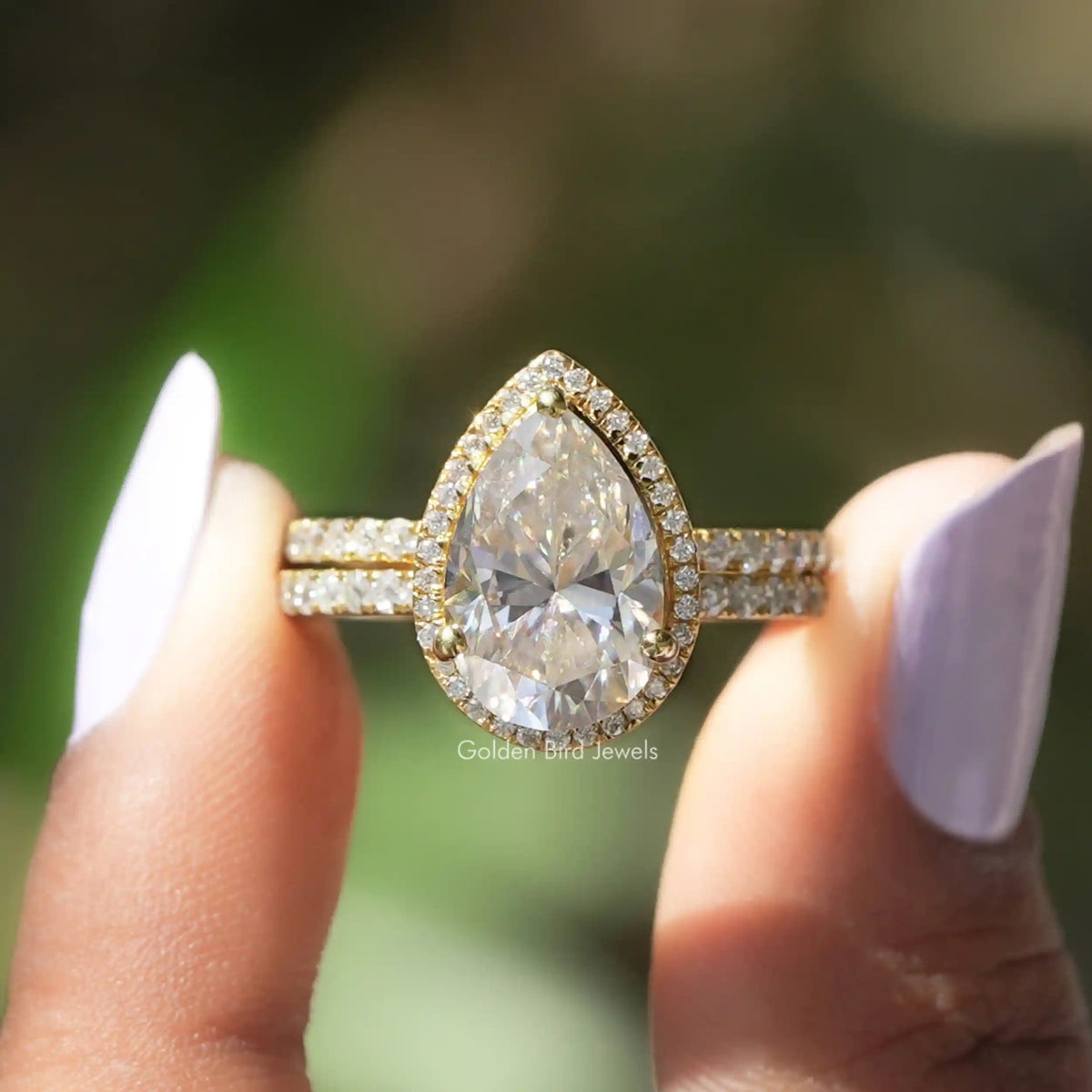 Two fingers holding the Pear Cut Moissanite Engagement Ring