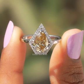 Two fingers holding the Pear Shaped Moissanite Halo Ring