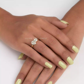 In finger front view of Asscher and pear cut moissanite  ring in prongs setting 