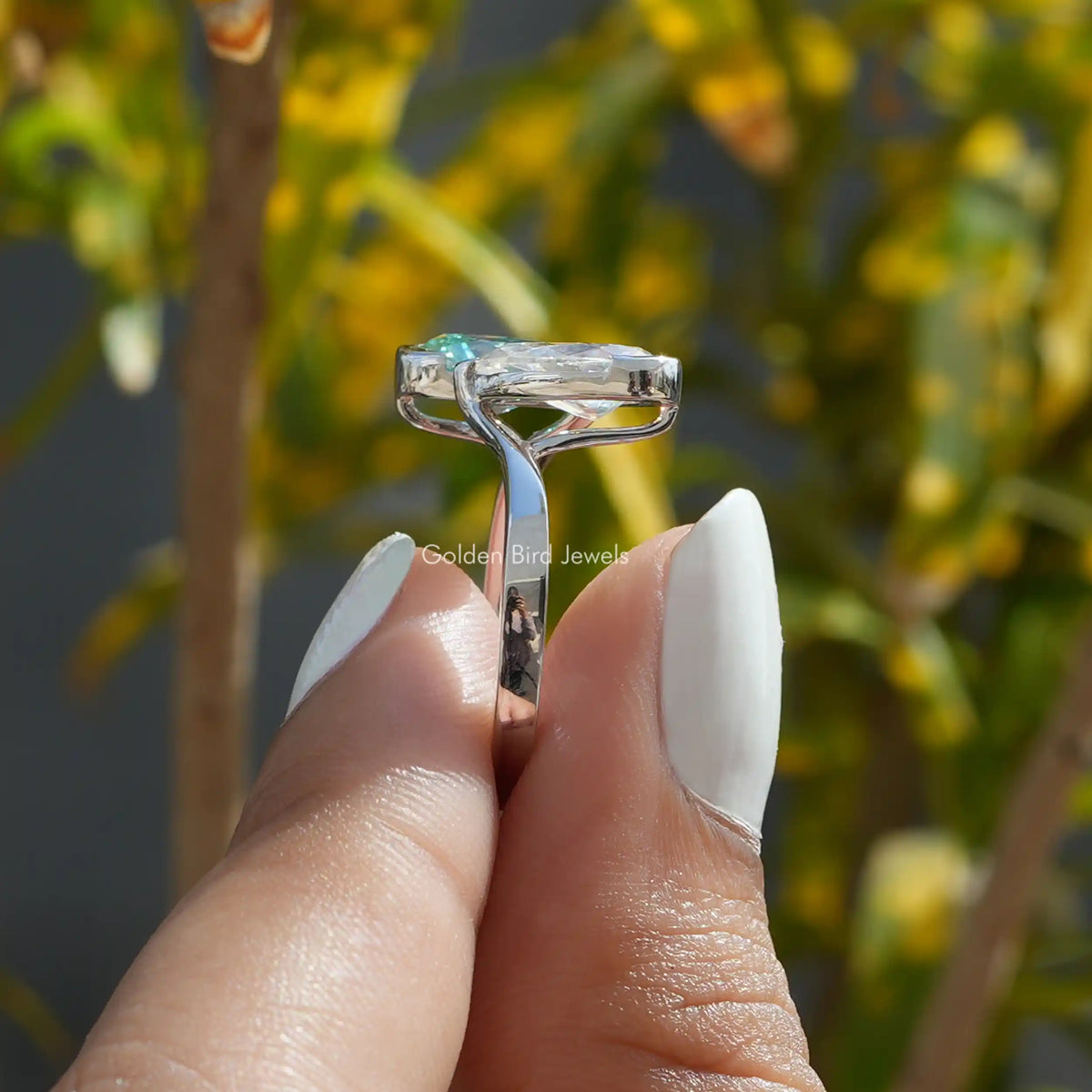 Close up view  of a women’s halo engagement ring holding  on two fingers 