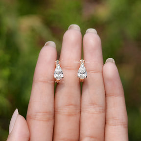 Front View of Pear Cut Solitaire Huggie Hoop Earrings In Fingers